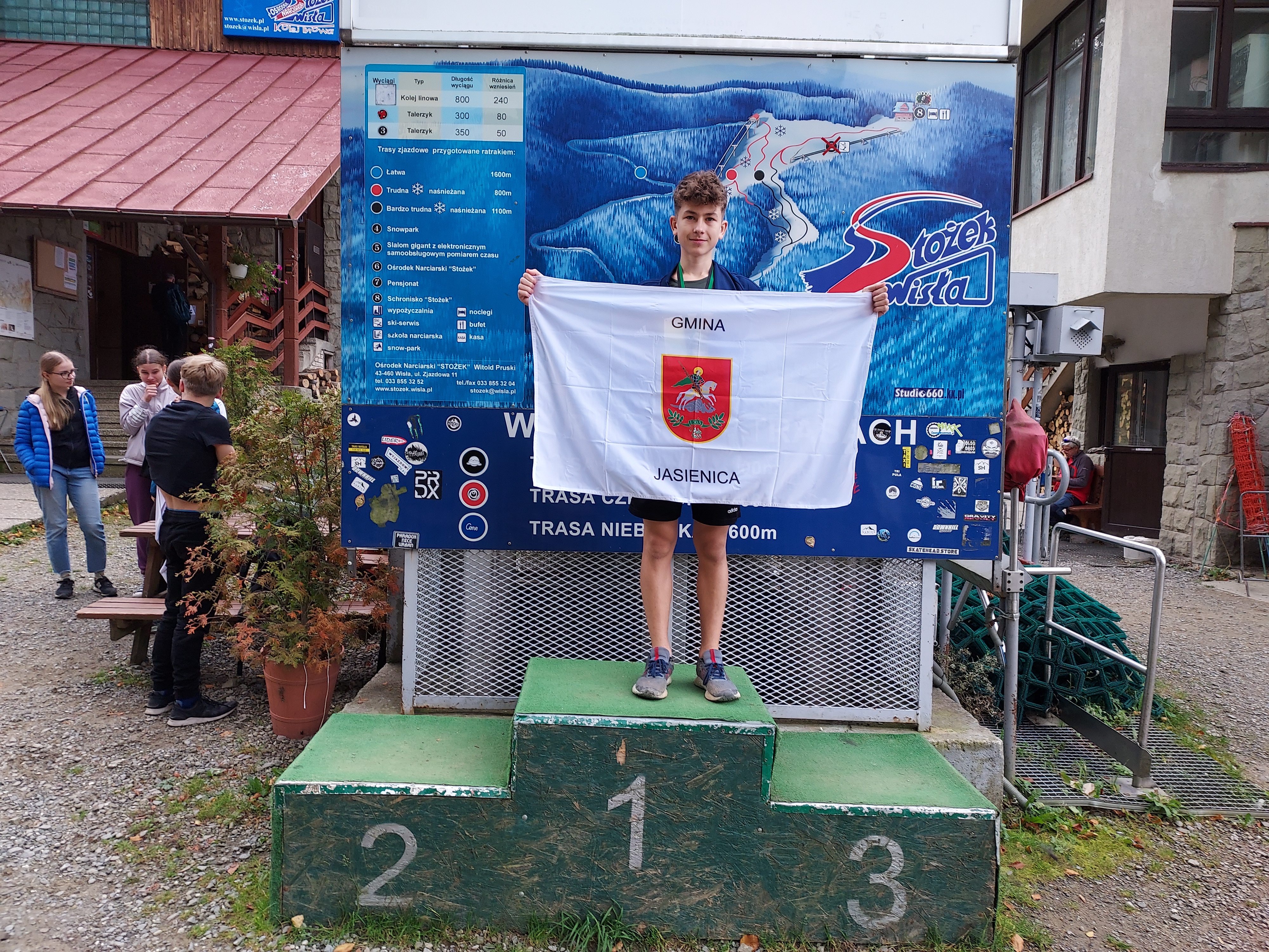 Piotr Talik stojący na podium Mistrzostw Śląska z flagą gminy Jasienica. 