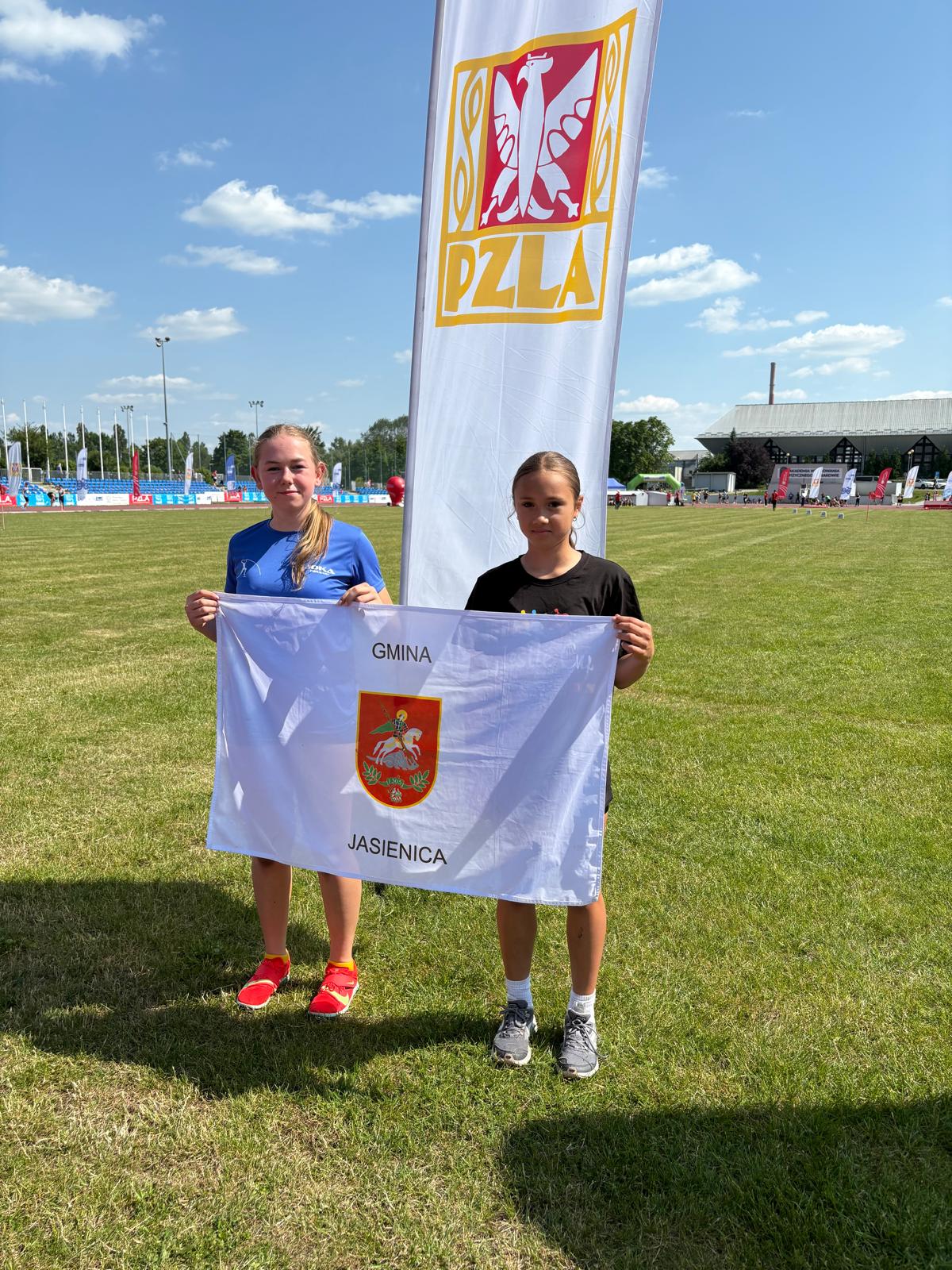 Zawodniczki UKS Olimp Mazańcowice trzymające baner z herbem gminy.