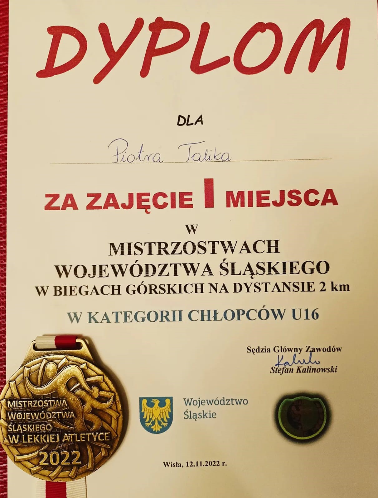 Dyplom dla Piotra Talika za zdobycie pierwszego miejsca wraz ze złotym medalem z wygrawerowaną nazwą zawodów Mistrzostw Województwa Śląskiego w Lekkiej Atletyce.